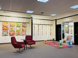 Artwork hanging on the walls with two chairs and children's activity area.