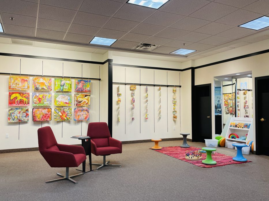 Artwork hanging on the walls with two chairs and children's activity area.