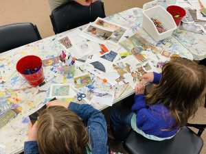 Two children using scissors to cut out paper.