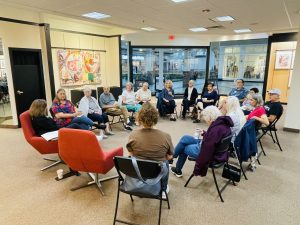 A group of people seated in a circle in an art gallery.