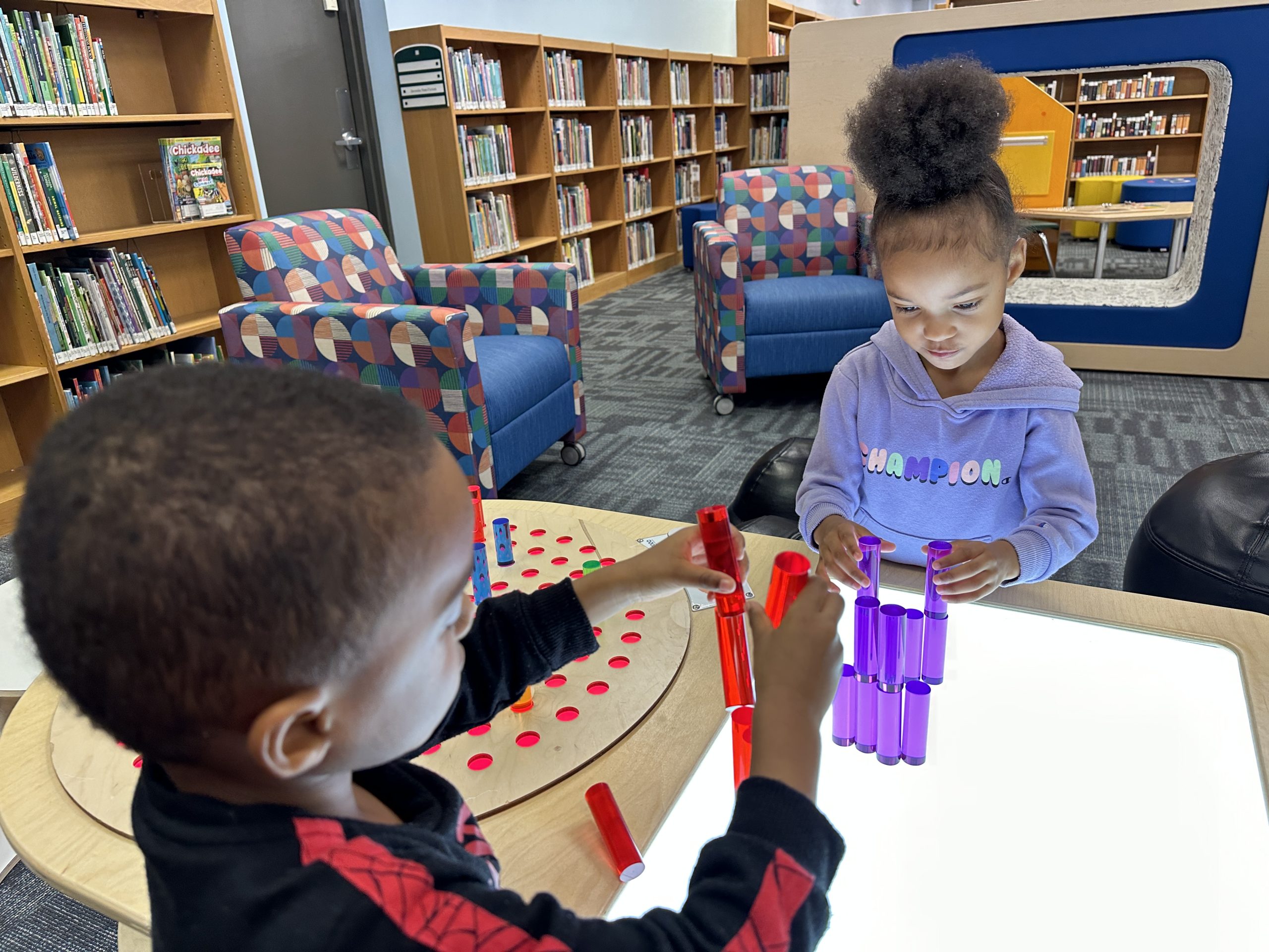 two young children play with a light table at the library