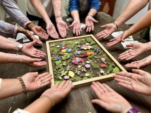 hands surround a frame of finished flower art, showing off the work they created together. 