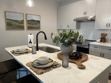 Kitchen island in apartment home with artwork and cabinets behind