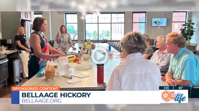 Female cooking instructor in front of attendees gathered around a large island